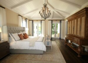 Stylish bedroom interior featuring a rustic chandelier, cozy bedding, and elegant wooden furniture.